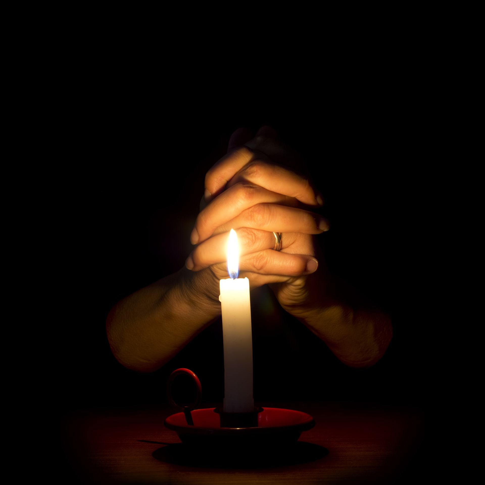 Religious image. Closeup of female hands in prayer, retro candlestick.